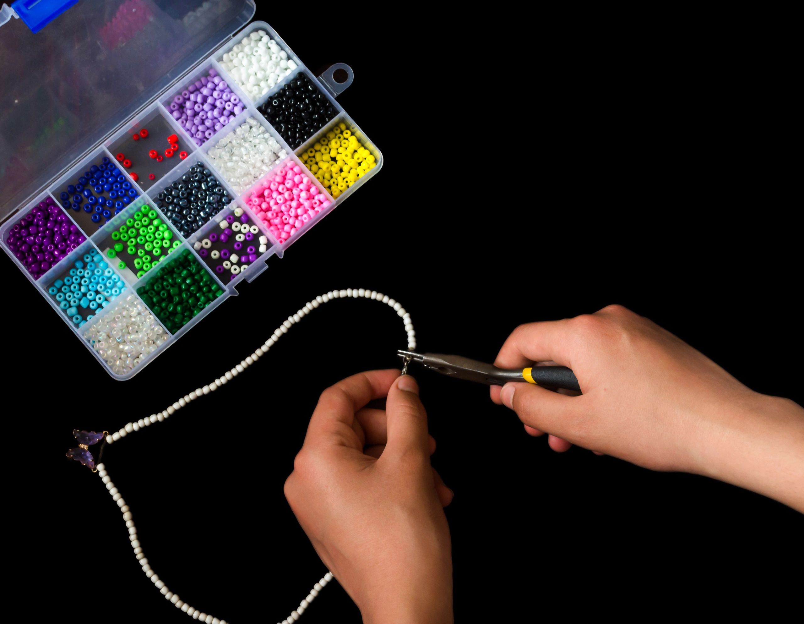 Hands making a handmade bracelet with beads
